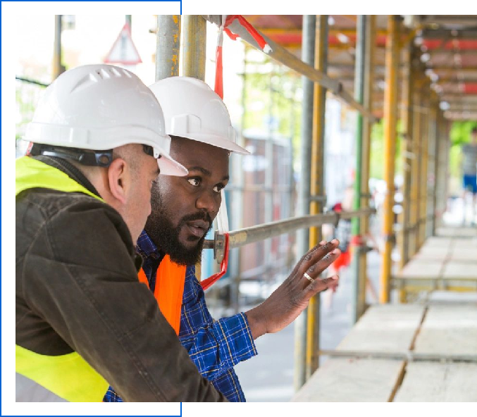 Two men in hard hats looking at a building